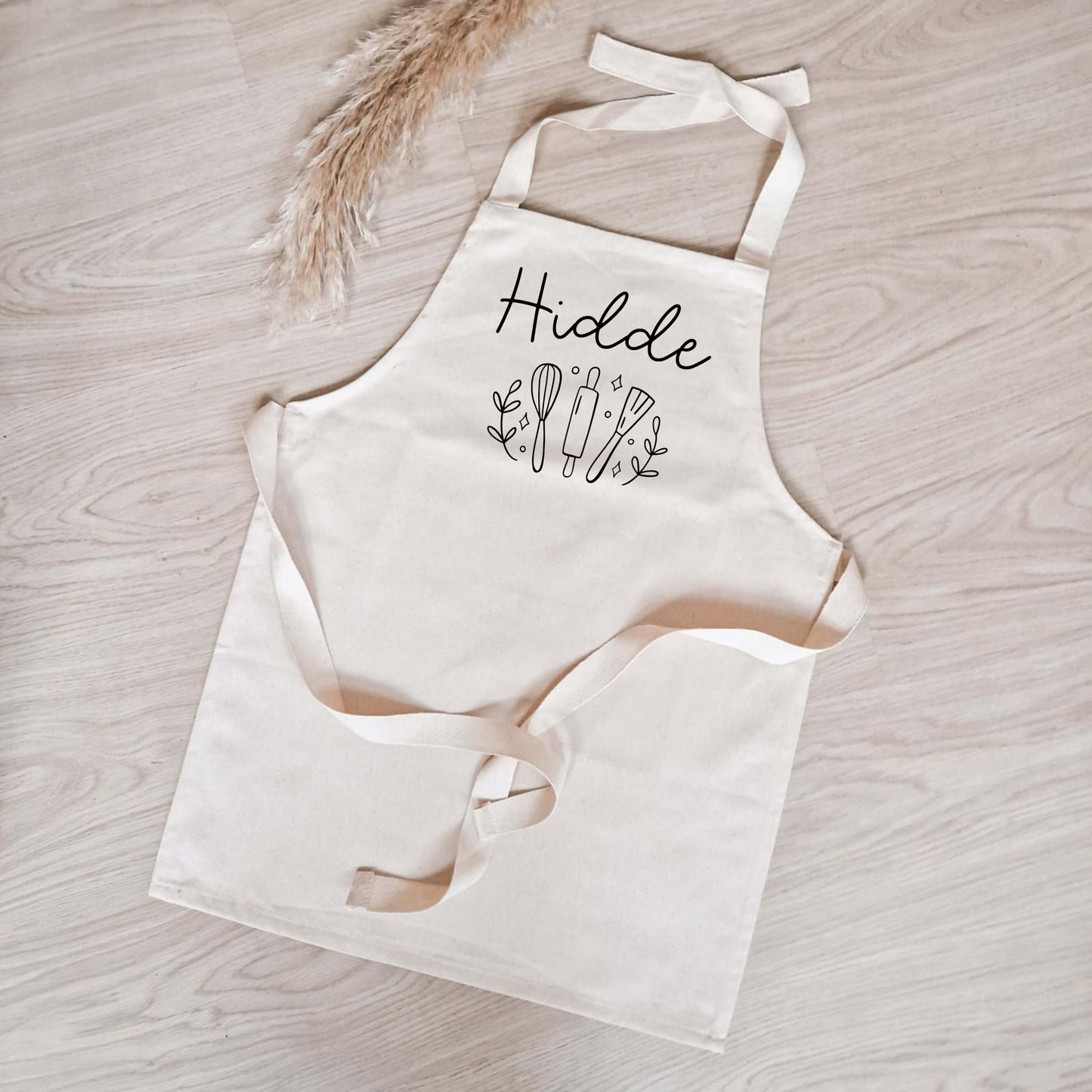 Katoenen kinderschort met naam met een afbeelding van keukengerei (garde, deegroller, spatel)