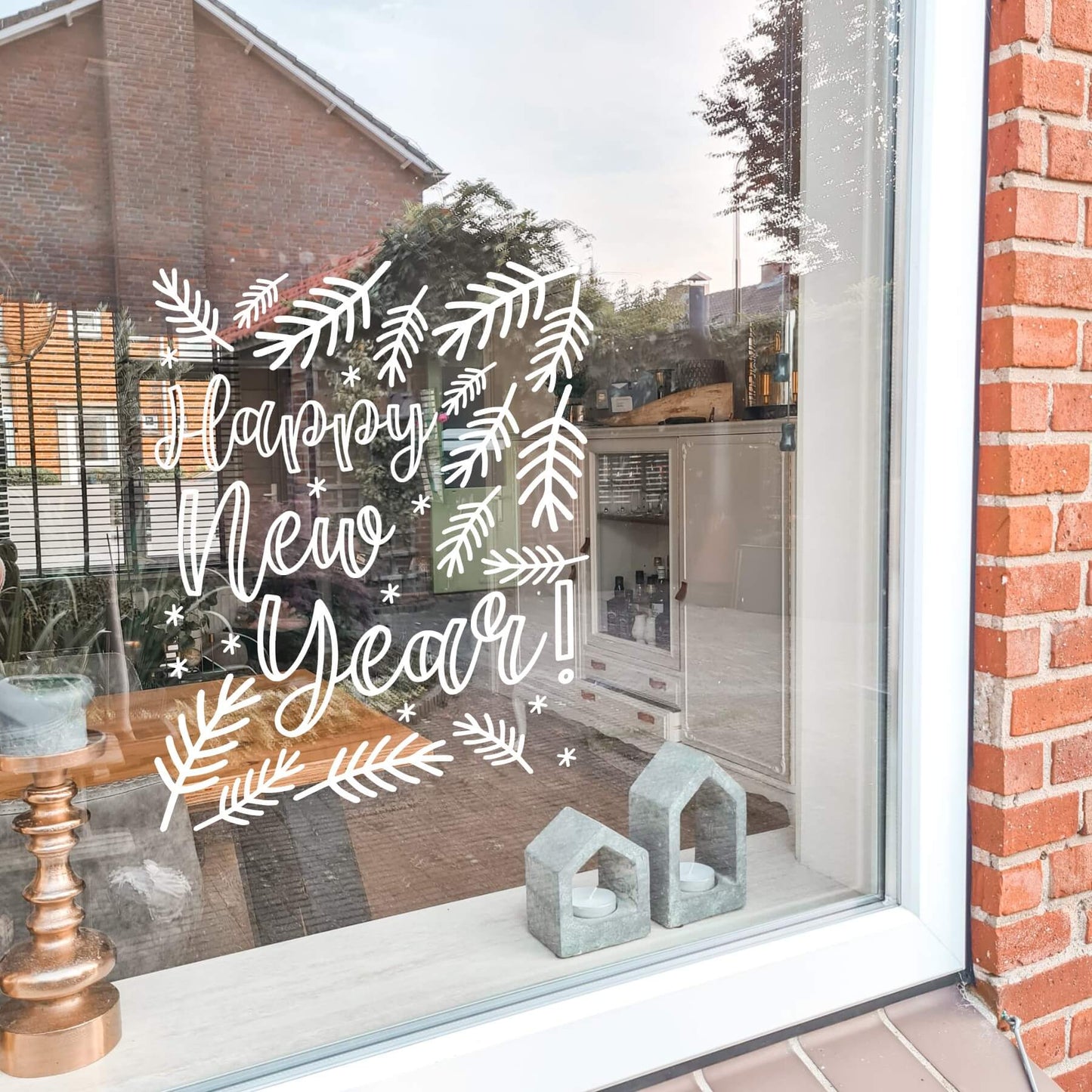 Raamsticker met bladeren en de tekst happy new year