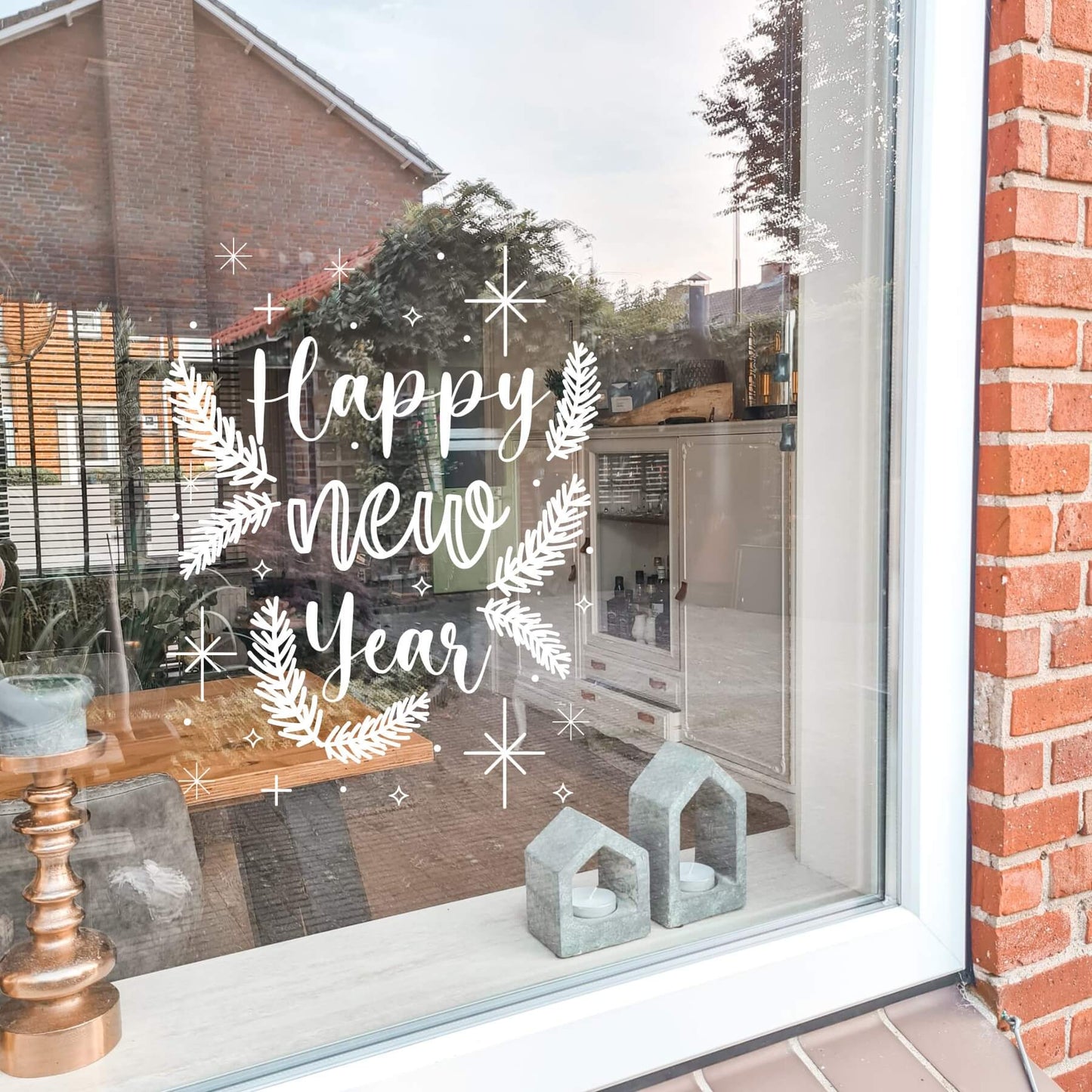 raamsticker met kersttakken en de tekst happy new year