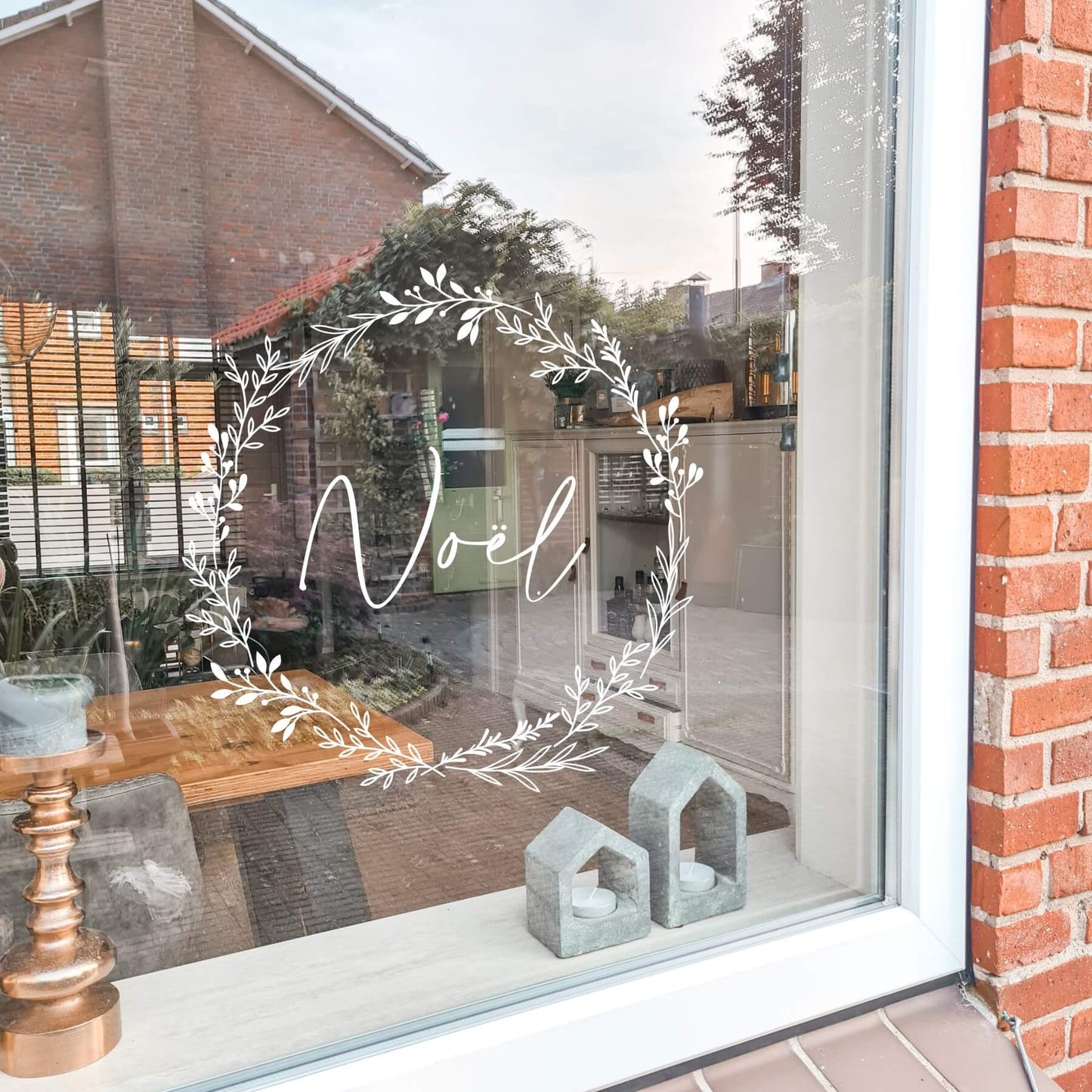 raamsticker met een krans van bladeren met de tekst noël