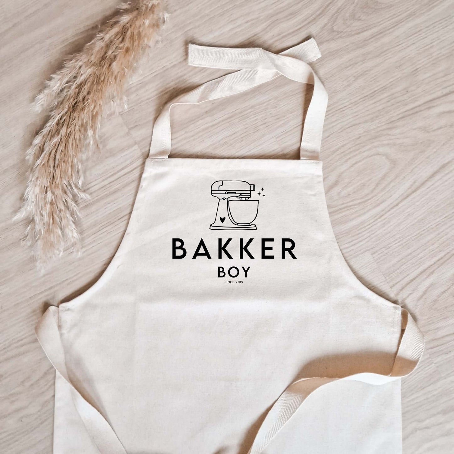 katoenen kinderschort met naam, keukenmixer met daaronder "Bakker" en zijn of haar naam en geboortejaar (close-up foto)