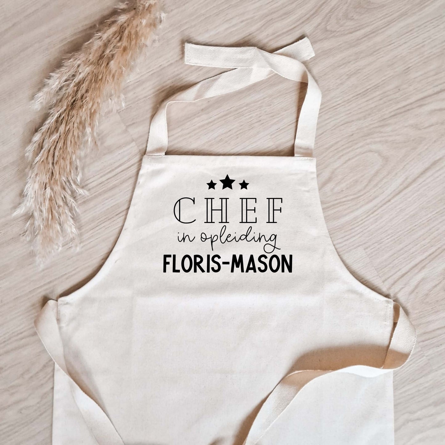 Kinderschort met naam met 3 sterren met de tekst "chef in opleiding" met daaronder de naam (close-up foto)